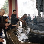 Family drinking from the holy water fountain at Sensoji Temple in Tokyo. Photo by alphacityguides.